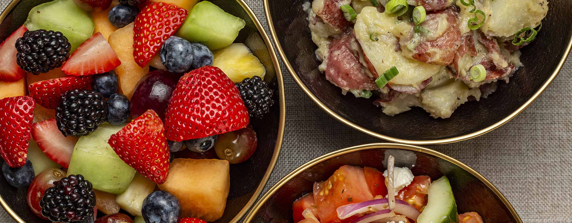 Katzinger's Fruit Salad, Redskin Potato Salad and Greek Salad in bowls.